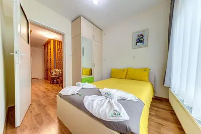 a small bedroom with a yellow bed with towels on it at Къща за гости Хаджиевата къща in Smolyan