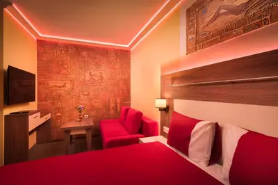 a bedroom with a red bed and a red chair at АРТ СТУДИО СОФИЯ in Sofia