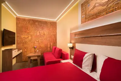 a bedroom with a red bed and a red chair at АРТ СТУДИО СОФИЯ in Sofia