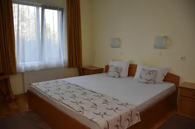 a bedroom with a large white bed with a window at Хотел Сима in Beklemeto