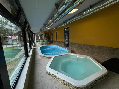a large jacuzzi tub in a building with a pool at Хотел Сима in Beklemeto