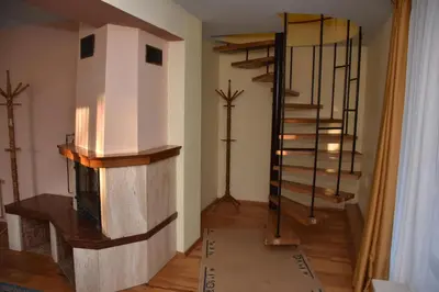 a living room with a fireplace and a spiral staircase at Хотел Сима in Beklemeto