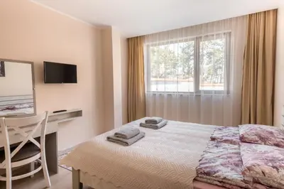 a bedroom with a bed and a desk and a window at Апартамент В4 in Velingrad