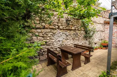 a wooden table and benches in front of a stone wall at Toni's Guest House in Melnik