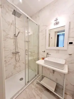 a white bathroom with a shower and a sink at Hotel House K21 in Sofia