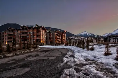 a snow covered street in front of some buildings at Saint Ivan Ski Apartments in Bansko