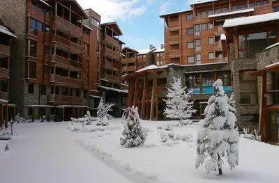 a courtyard covered in snow with trees and buildings at Saint Ivan Ski Apartments in Bansko