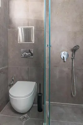 a bathroom with a toilet and a glass shower stall at Industrial 2-BDR Flat by the National Stadium by Flat Mаnager in Sofia