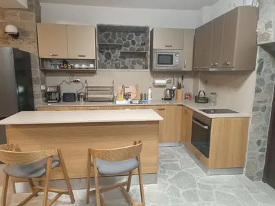 a kitchen with a counter and two chairs in it at Червената къща in Perushtitsa