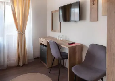 a room with a desk with two chairs and a television at Червената къща in Perushtitsa