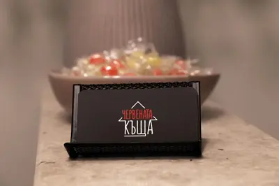 a black sign on a table next to a bowl of food at Червената къща in Perushtitsa
