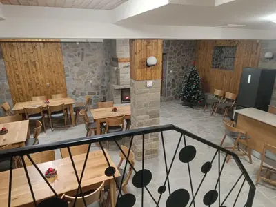 a restaurant with wooden tables and chairs and a christmas tree at Червената къща in Perushtitsa