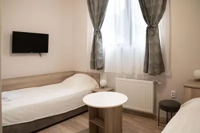 a small bedroom with two beds and a tv at Червената къща in Perushtitsa