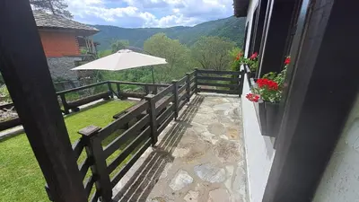 a balcony with an umbrella and a fence at Авина къща in Kovachevitsa