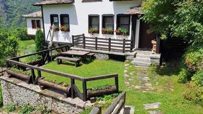 a house with a picnic bench in front of it at Авина къща in Kovachevitsa