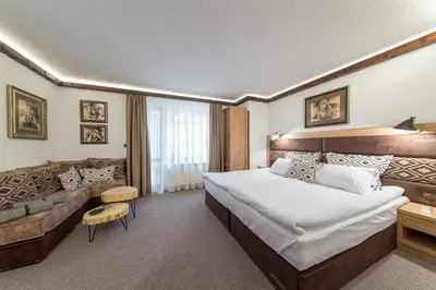 a hotel room with a large bed and a couch at Българче Хотел - Ресторант in Smolyan