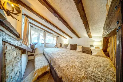 a large bed in a room with a stone wall at Българче Хотел - Ресторант in Smolyan