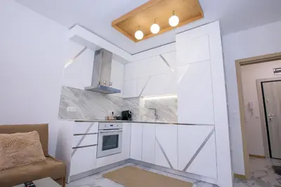a kitchen with white cabinets and a couch in a room at Лукс Апартамент Радост 2 in Sandanski