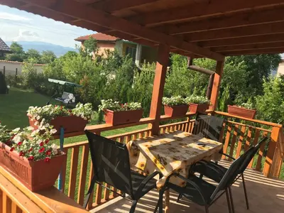 a wooden table and chairs on a deck with potted plants at Къщи за гости Михайлови in Sapareva Banya