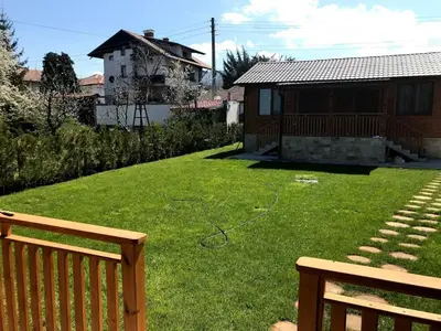 a yard with a wooden bench and a house at Къщи за гости Михайлови in Sapareva Banya