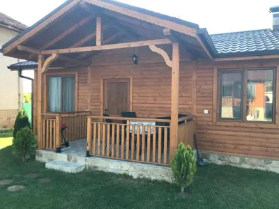 a cabin with a wooden deck with a porch at Къщи за гости Михайлови in Sapareva Banya