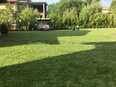 a park with a bench in the middle of the grass at Къщи за гости Михайлови in Sapareva Banya