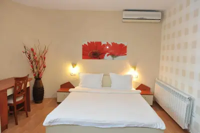 a bedroom with a white bed with a desk and a table at Eros Motel in Sandanski