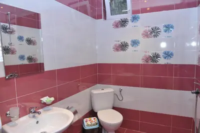 a red and white bathroom with a toilet and a sink at Eros Motel in Sandanski