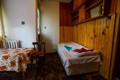 a room with a bed and a table and a bed sidx sidx sidx at Topuzovi Guest House in Dobrinishte