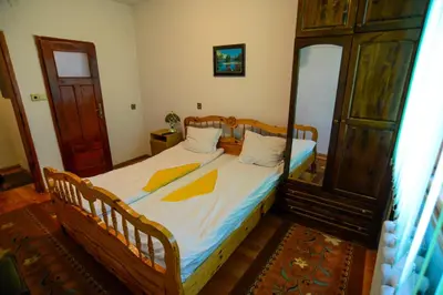 a bedroom with a bed and a wooden cabinet at Topuzovi Guest House in Dobrinishte