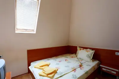 a small bedroom with a bed with yellow towels on it at Acropolis Hotel in Pazardzhik