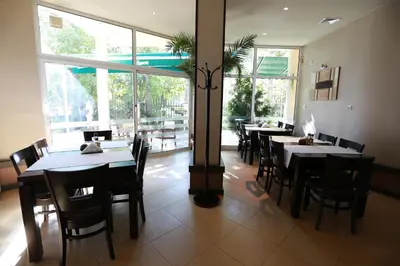 a restaurant with tables and chairs and a large window at Acropolis Hotel in Pazardzhik