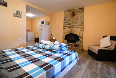 a bedroom with a bed and a stone fireplace at КЪЩА ЗА ГОСТИ “НИЯ” in Smolyan