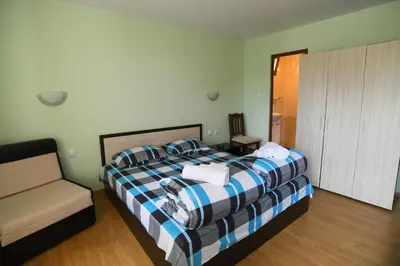 a bedroom with a bed with a couch and a chair at КЪЩА ЗА ГОСТИ “НИЯ” in Smolyan