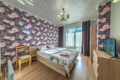 a bedroom with a bed and a tv and flowers on the wall at Sweet Home апартамент 530 Смолянски езера in Smolyan