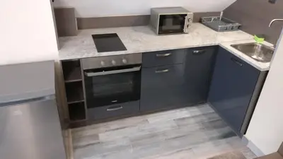 a small kitchen with a stove and a sink at Къща за гости Роял in Sandanski