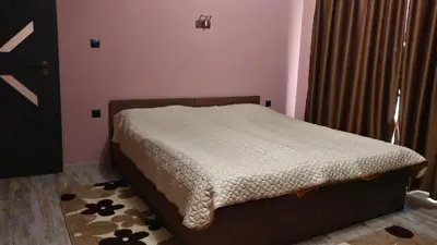 a small bed in a bedroom with pink walls at Къща за гости Роял in Sandanski