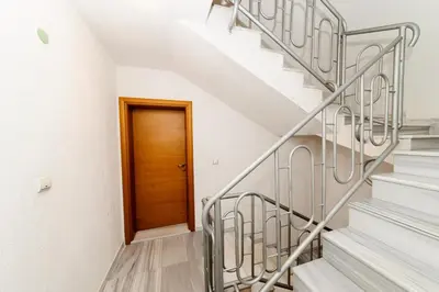 a staircase with a wooden door in a white house at Orchideia Studios in Sandanski