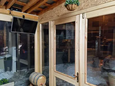 a screened porch with glass doors and a television at Къща Томови,стаи за гости in Devin
