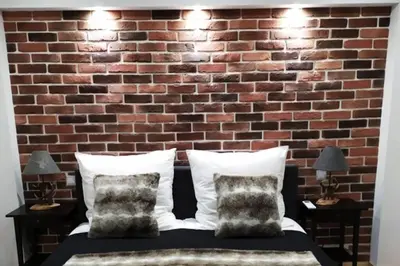 a bedroom with a brick wall and a bed with pillows at GUESTHOUSE MARIA / КЪЩА ЗА ГОСТИ МАРИЯ / GÄSTEHAUS MARIA in Karlovo