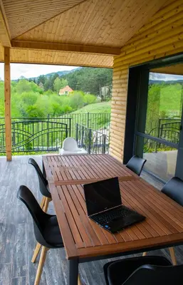 a laptop computer sitting on a wooden table on a patio at Villa Dea & Villa Ina - Villas & SPA Park in Velingrad by Flat Mаnager in Velingrad