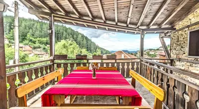 a wooden table with a red table cloth on a balcony at Къща Стара Македония in Gostun
