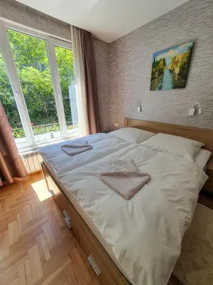 a large white bed in a room with windows at Roza Home in Sofia