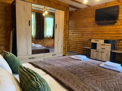a bedroom with a large bed and a tv on the wall at Тихият кът in Sapareva Banya