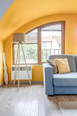 a yellow living room with a blue couch and a tripod at Park Loft next to Eagle's Bridge in Sofia