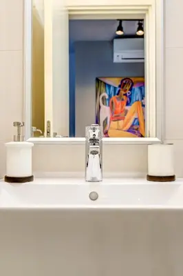 a bathroom with a sink with a mirror and a faucet at Park Loft next to Eagle's Bridge in Sofia