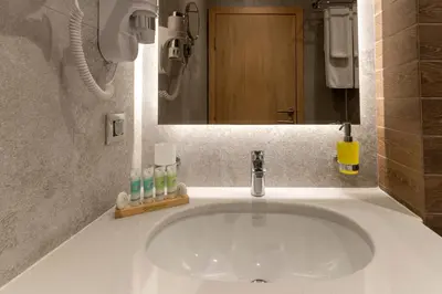 a white sink in a bathroom with a mirror at City Park Inn in Plovdiv