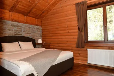 a bedroom with a bed in a wooden room at Moiata Kashta Villa in Popovi Livadi