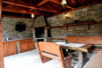 a kitchen with a wooden table and a stone wall at Moiata Kashta Villa in Popovi Livadi
