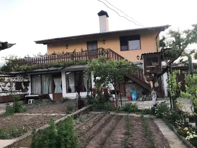 an old house with a garden in front of it at Къща за гости Градината in Dobrinishte